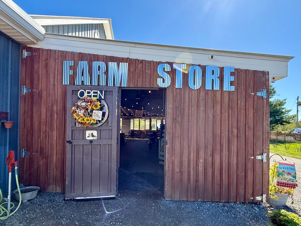 The rustic Farm Store entrance at Mackintosh Fruit Farm under a bright blue sky.